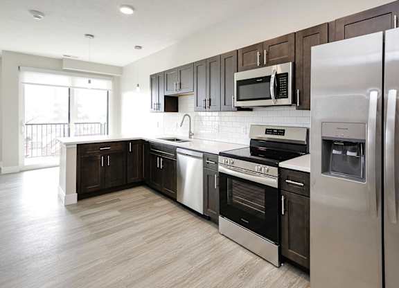 A modern kitchen with dark brown cabinets and stainless steel appliances.