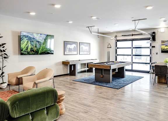 A room with a table, chairs, and a TV on the wall.
