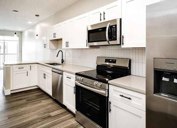 A modern kitchen with white cabinets and stainless steel appliances.
