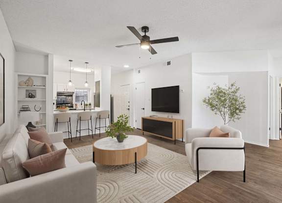 A living room with a white couch, a wooden coffee table, and a ceiling fan.