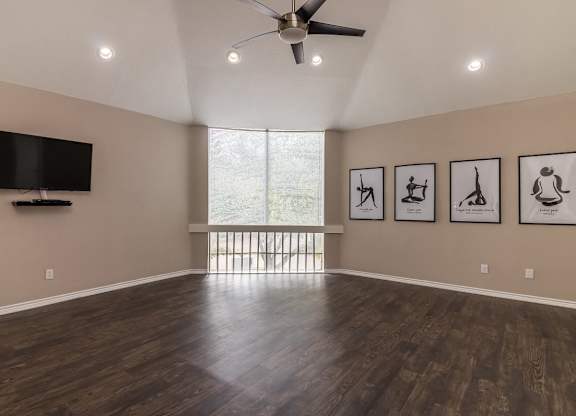 A spacious room with a television, a ceiling fan, and pictures on the wall.