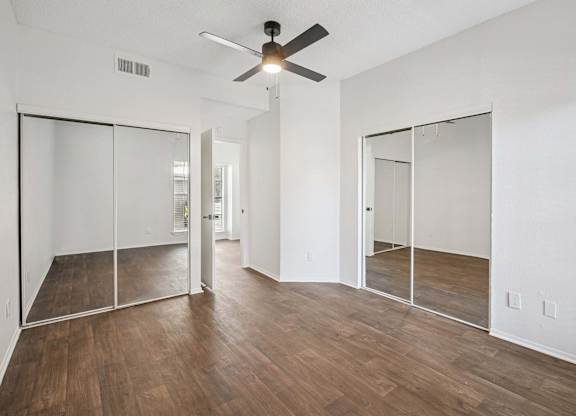 A room with a ceiling fan and wooden floors.