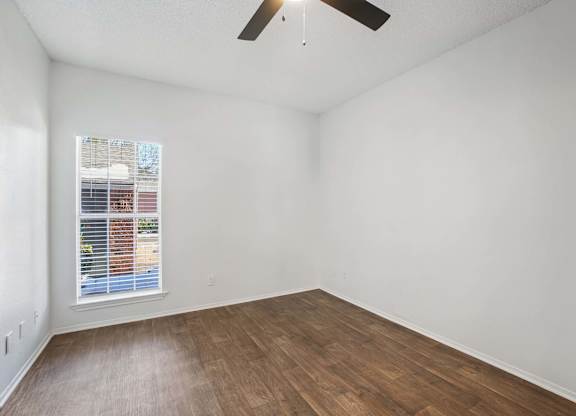 Empty room with a window and a ceiling fan.