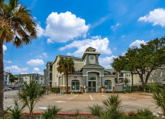 a large building with a parking lot and palm trees
