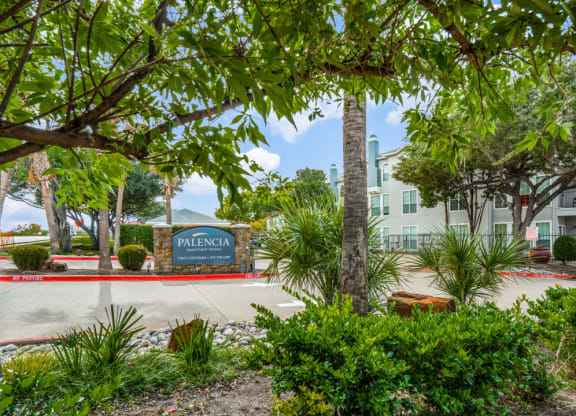 a building with a sign in front of trees and plants