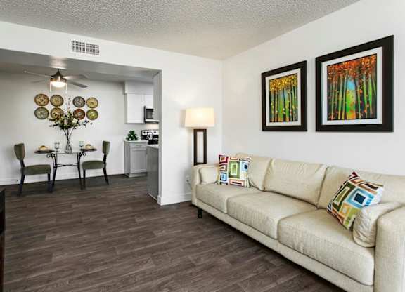 A living room with a couch, chairs, and pictures on the wall.