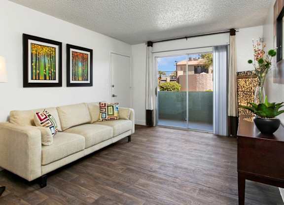 A living room with a couch, two pictures on the wall, and a sliding glass door.