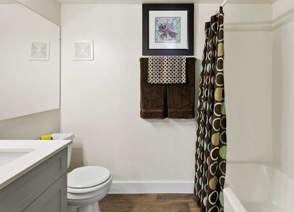 A bathroom with a toilet, sink, and a picture hanging on the wall.