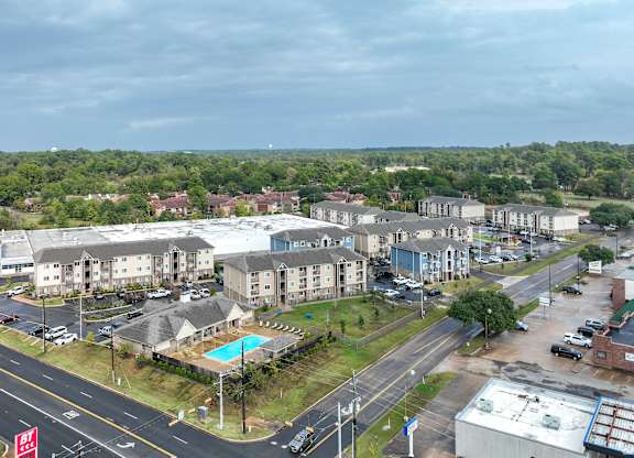 A large apartment complex with a pool in the middle of a parking lot.