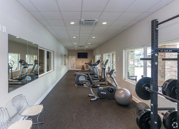 A gym with a variety of equipment including weights and treadmills.