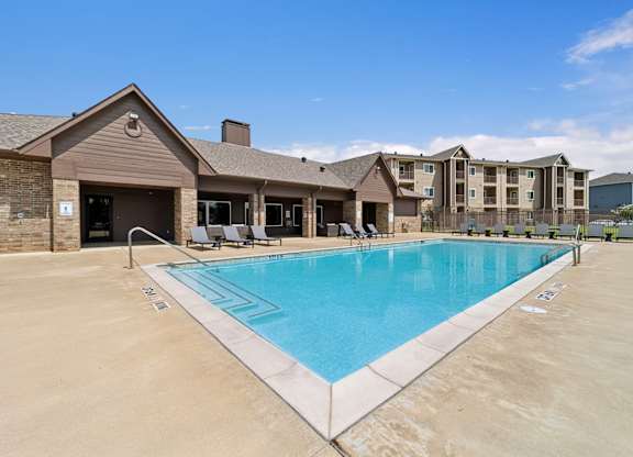 A large swimming pool in front of a building with a clear blue sky above.