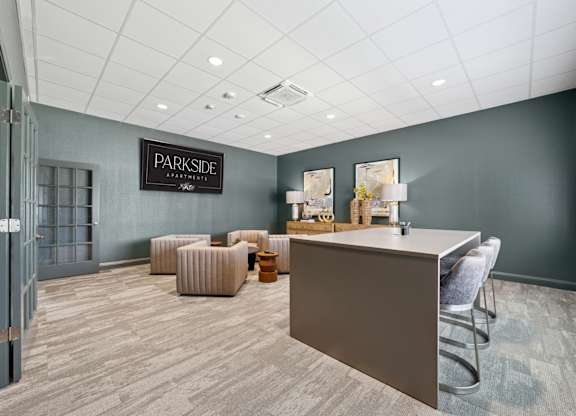 A reception area with a desk and chairs in a room with a grey wall and a door.