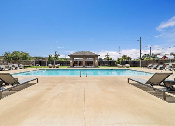 A large outdoor swimming pool with sun loungers and a pavilion.