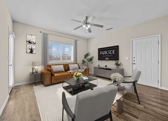 A living room with a brown couch, a coffee table, and a ceiling fan.