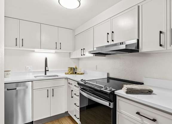 A modern kitchen with white cabinets and stainless steel appliances.