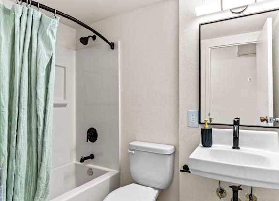 A white bathroom with a toilet, sink, and shower.