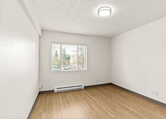 A room with a window and a white wall.