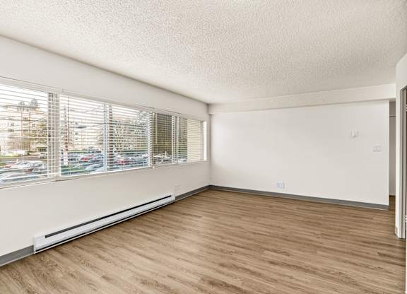 A room with wooden flooring and a window with blinds.