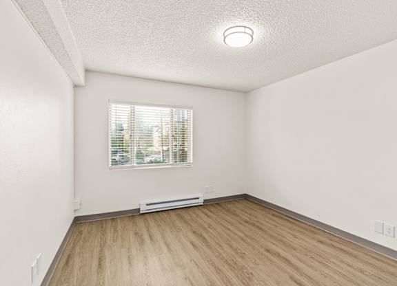A room with a window and a radiator on the floor.