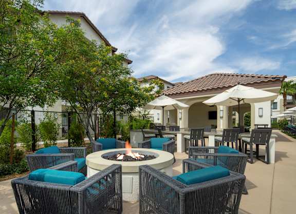 A patio with a fire pit and chairs.