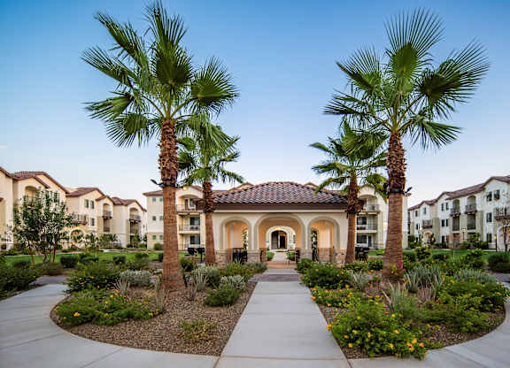 A beautifully landscaped entrance to a residential complex with palm trees and a central archway.