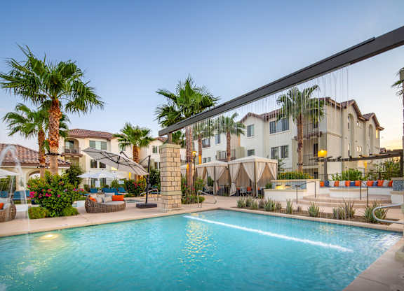 A pool surrounded by palm trees and buildings.