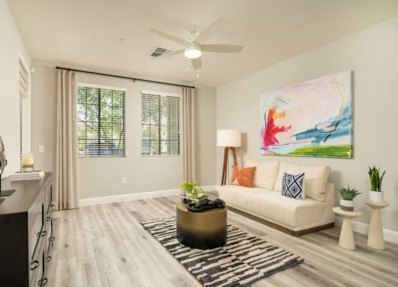 A living room with a large painting on the wall and a white couch.