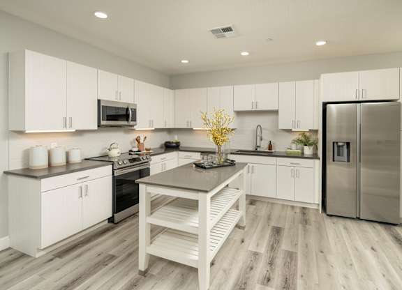 A modern kitchen with white cabinets and a wooden island.