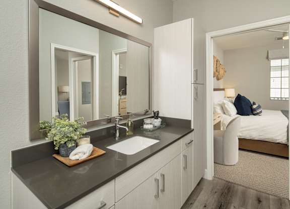 A bathroom with a double sink vanity and a mirror above it.