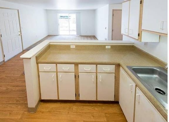 A kitchen with white cabinets and a wooden floor.