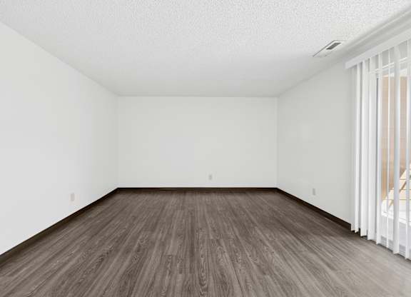 A room with wooden flooring and white walls.