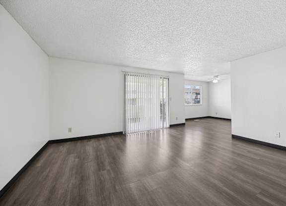 A room with a sliding glass door and wooden flooring.