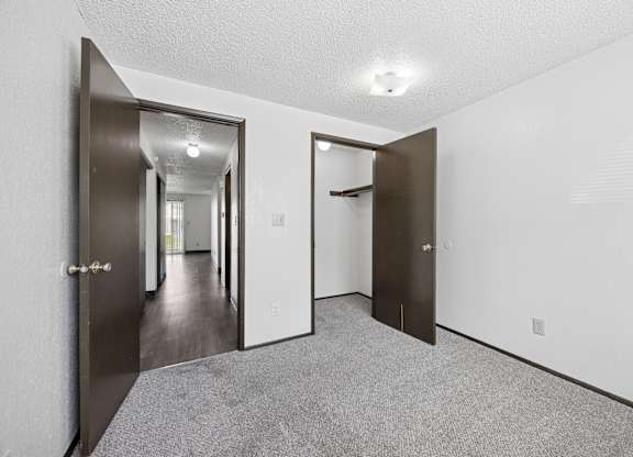 A hallway with a carpeted floor and white walls.
