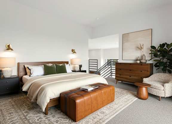 A bedroom with a large bed, a chair, and a painting on the wall.