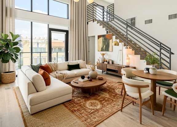 A living room with a staircase, a sofa, a table, and chairs.