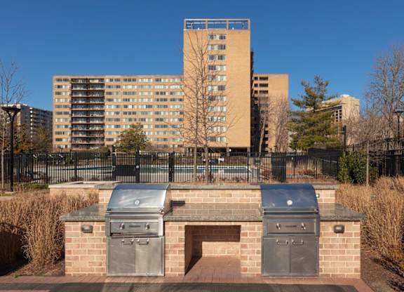A brick structure with two ovens on top of it in front of a tall building.