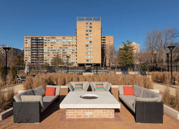 A patio with a table and chairs in front of a tall building.