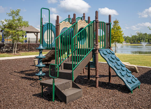 a playground with a slide and climbing equipment with a lake in the background
