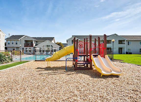 A playground with a yellow slide and red structure.