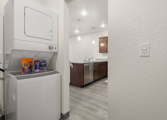 A white wall with a light switch and a white fridge with a bag of Tostitos on top.