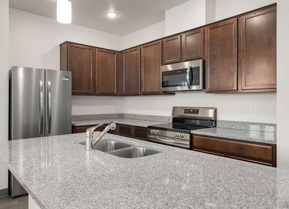 A kitchen with a granite countertop and stainless steel appliances.