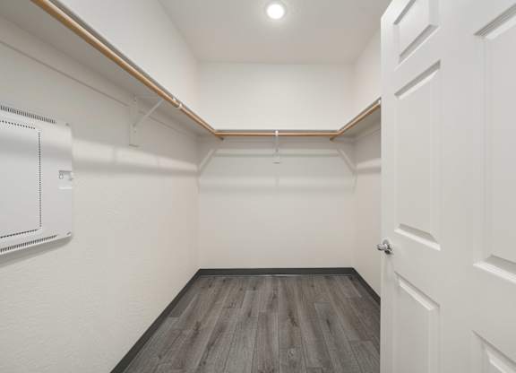 A white door is on the right side of a room with wood flooring.