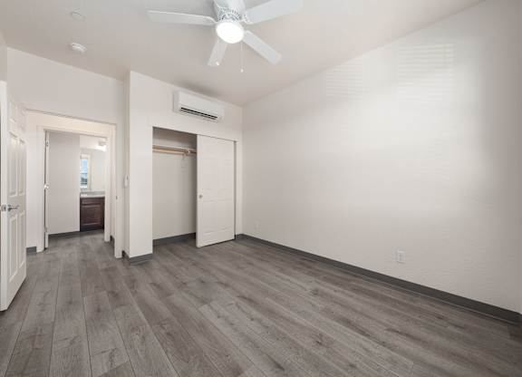 A room with a ceiling fan and wooden flooring.