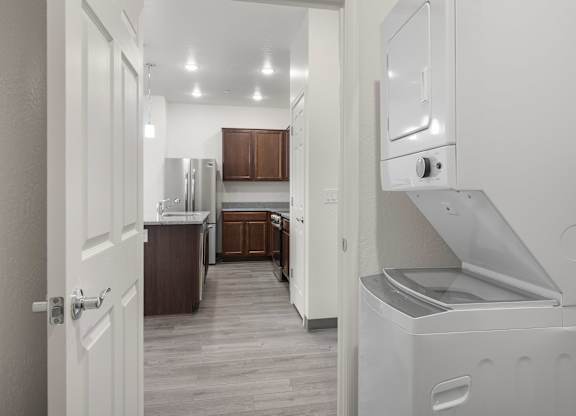 A white door is open to a kitchen with a refrigerator and oven.
