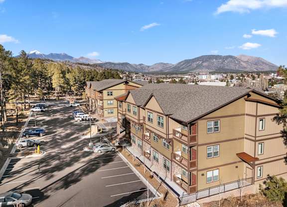 A parking lot in front of a building with a mountain in the background.