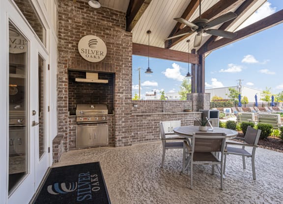 a patio with a table and chairs and a grill