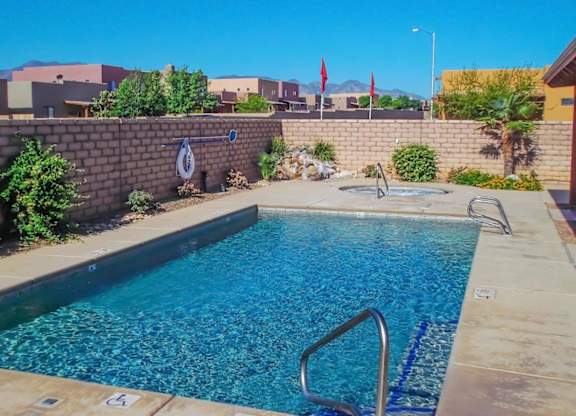 A swimming pool surrounded by a wall and some plants.