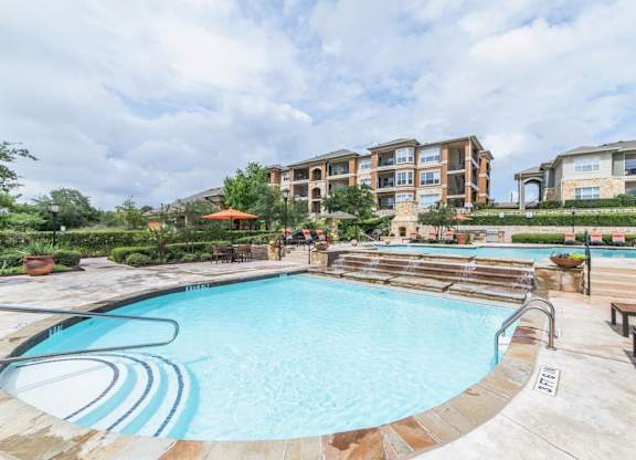 A large outdoor swimming pool with a slide and a building in the background.