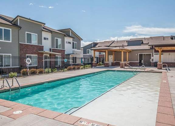 A swimming pool surrounded by a brick border and a fence with a sign that says "No Diving".