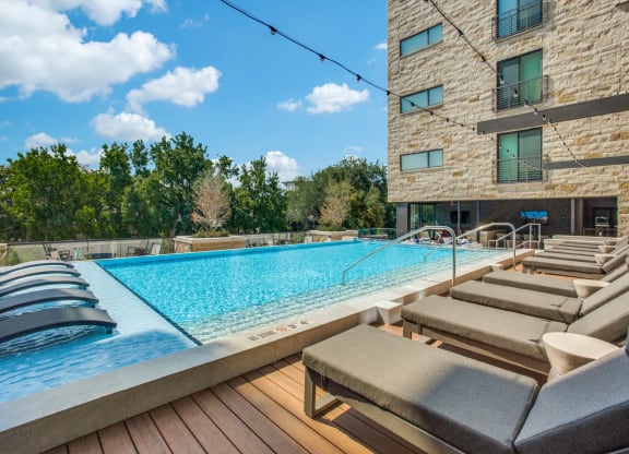 a pool with lounge chairs and a building in the background